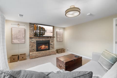 A stylish living room with a brick fireplace, gray couch, and decorative elements.