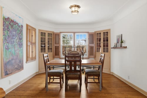 Gather around your elegant dining table with built-in cabinetry and warm wood floors creating the perfect spot for memorable meals.