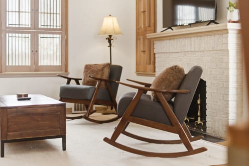 Unwind in your stylish living room featuring mid-century rocking chairs and a large sectional leather sofa, where warm wood tones and soft lighting create the perfect retreat.