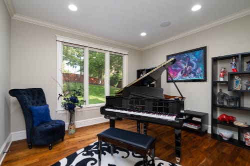 Unwind in your elegant music room featuring a grand piano, plush seating, and peaceful garden views.
