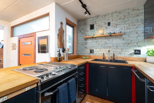 Cook delicious meals in your fully equipped kitchen featuring beautiful wood countertops, modern appliances, and rustic brick accent wall.