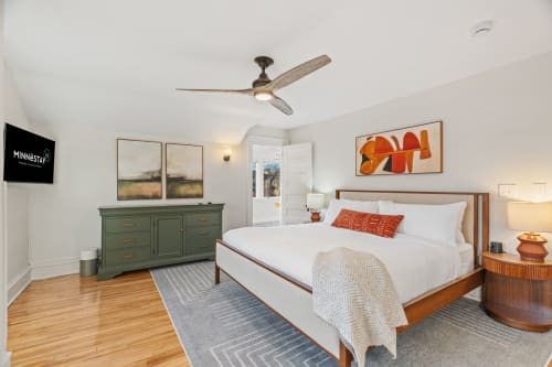 Drift off in your serene bedroom sanctuary with crisp linens, warm wood tones, and thoughtful artistic touches creating the perfect retreat.