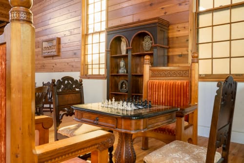 Step into your elegant game room where ornate wooden furnishings and a beautiful chess set await your strategic moments of relaxation.
