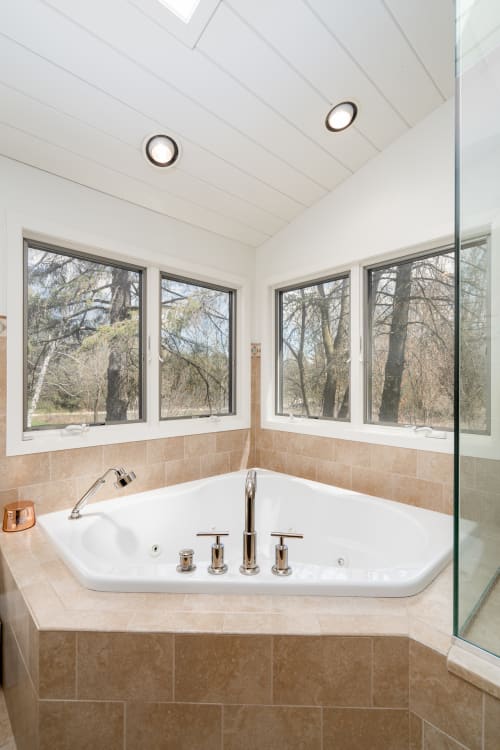 Soak away your stress in this luxurious corner tub with beautiful tree views streaming through oversized windows.