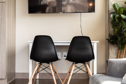 Your modern workspace awaits with a clean white desk, stylish seating, and entertainment - perfect for remote work or relaxing.