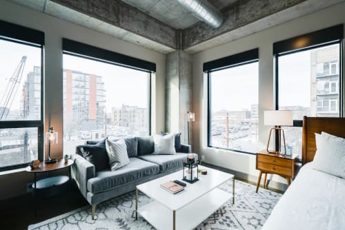 Unwind in your stylish living room with soaring windows showcasing vibrant city views while you relax on plush seating.