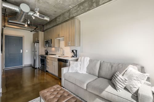 Relax in your modern loft with industrial charm, featuring exposed concrete ceilings, a fully equipped kitchen, and comfortable living space with stylish furnishings.