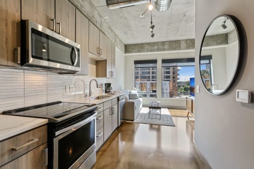 Your modern loft welcomes you with sleek concrete ceilings, warm wood cabinetry, and stunning city views from floor-to-ceiling windows.