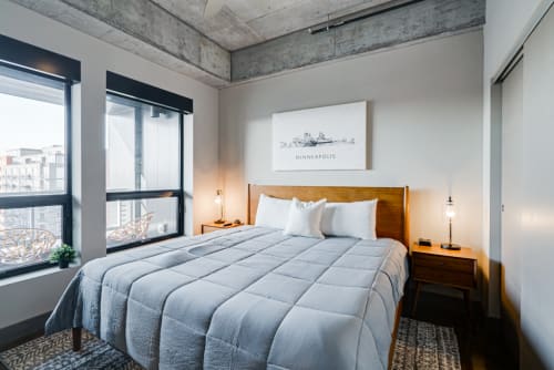 Sink into crisp linens and cozy textures in your modern urban retreat, where natural light flows across exposed concrete and warm wood finishes.