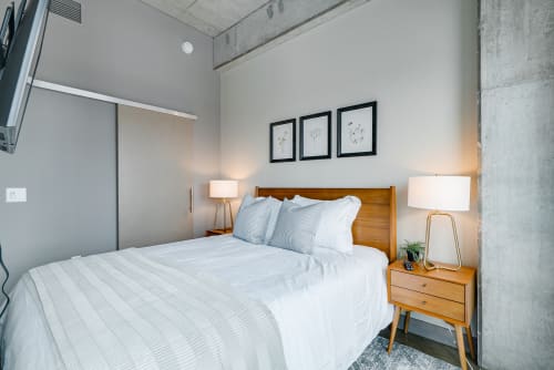 Rest peacefully in your modern bedroom with crisp linens, warm lighting, and stylish mid-century furnishings creating the perfect urban retreat.