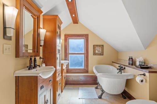 Soak your cares away in this charming clawfoot tub, surrounded by warm wood accents and natural light streaming through the window.